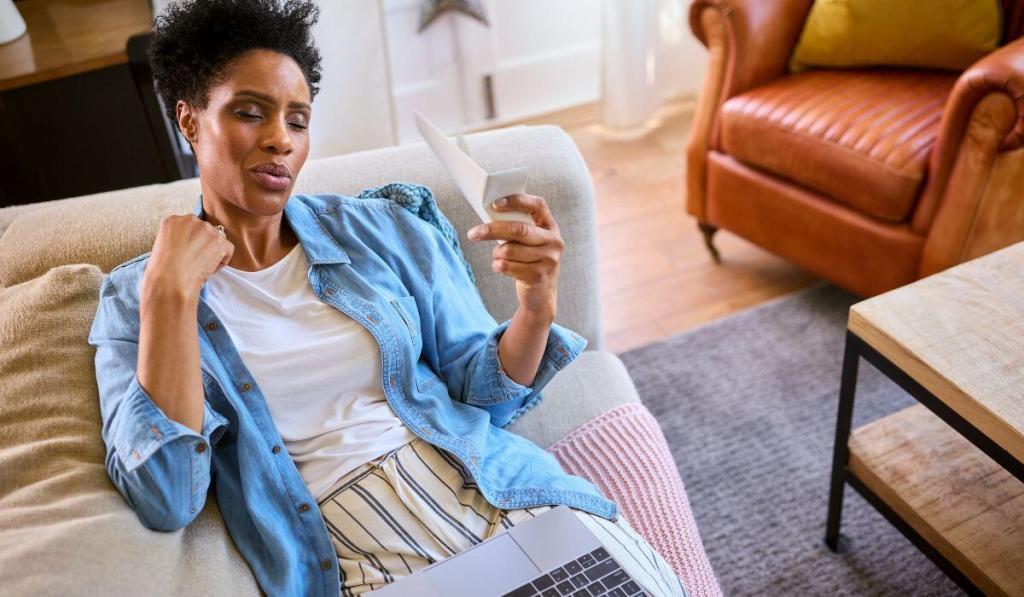 A dark-skinned woman looking at a piece of paper.
