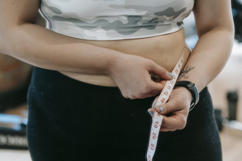 Close-up of a woman's waist being measured with a tape. Fitness and health concept.