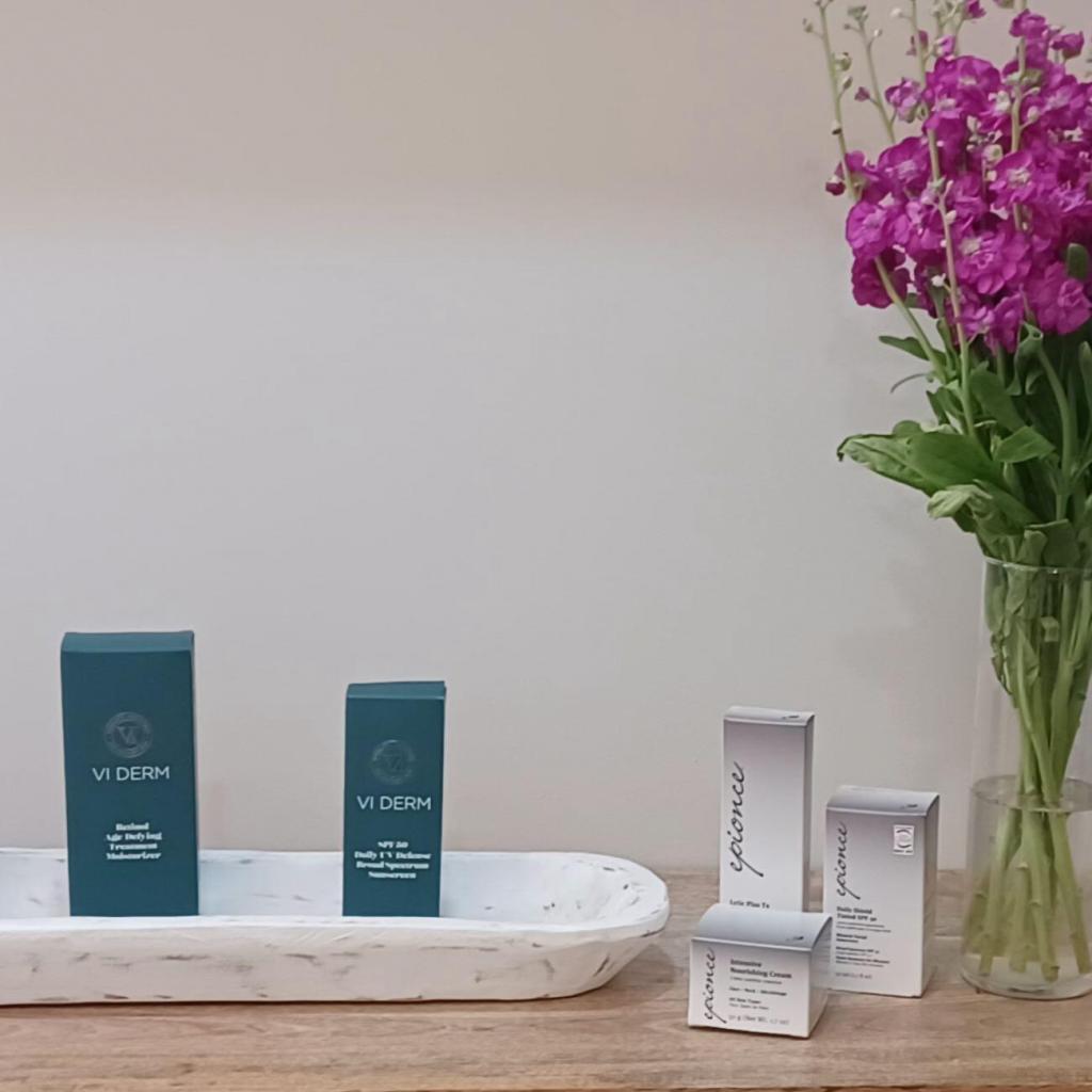 Skin care products on a beautiful wooden table with purple spring flowers.