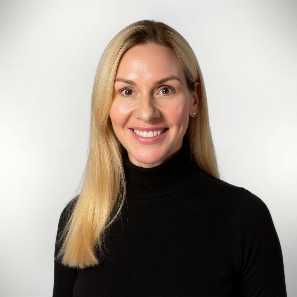 Carrie has long blonde hair and is wearing a black turtleneck shirt.